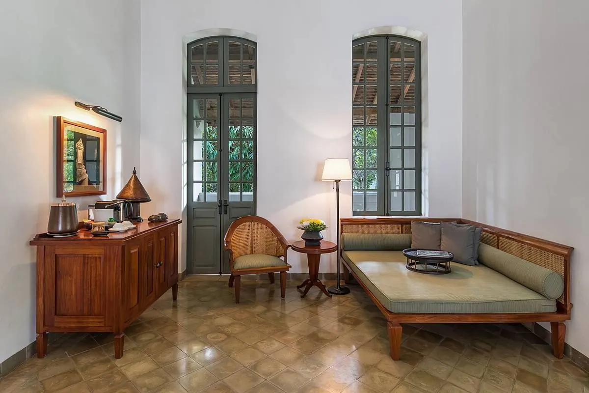 Pared-back living room: daybed, wooden sideboard, floor lamp and tall French windows