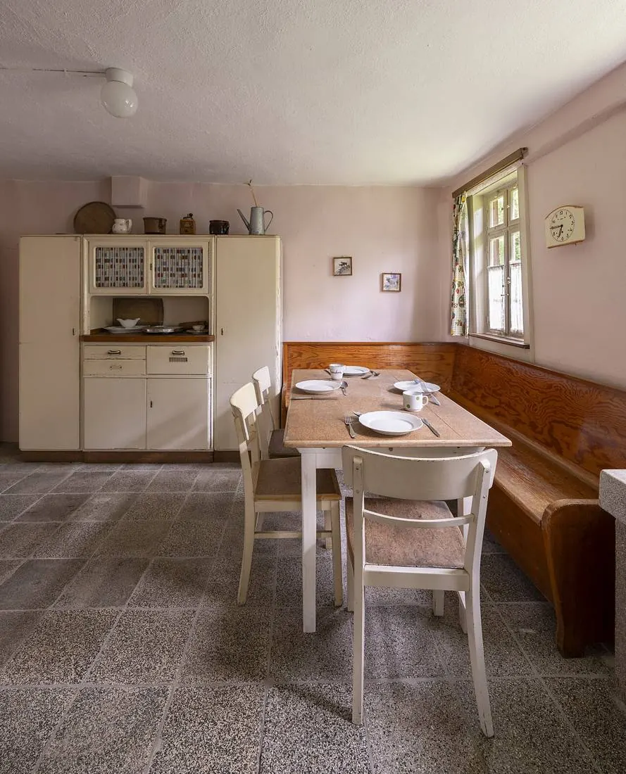 Simple kitchen with corner bench, white table and dresser